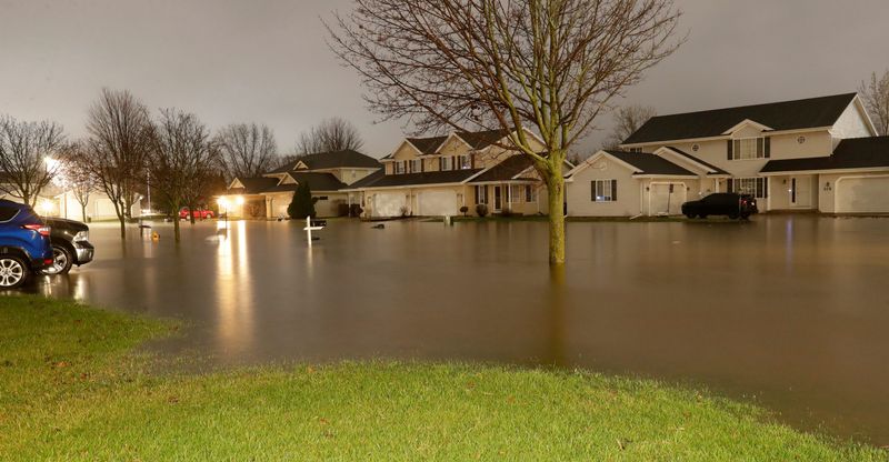 A street and yards flood during heavy rainfall on April 14, 2026, in De Pere, Wis.
