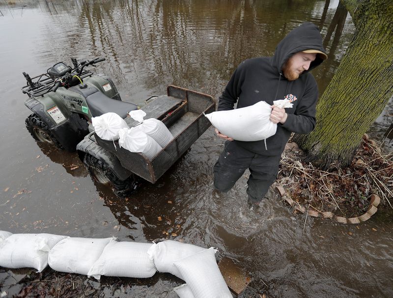 Mason Bumen uses sandbags to keep water away from the foundation of his home as floodwater continues to rise Thursday, April 16, 2026, in Shiocton, Wis.