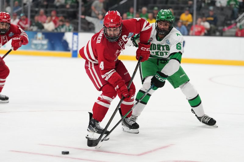 Apr 9, 2026; Las Vegas, Nevada, UNITED STATES; Wisconsin Badgers defenseman Ben Dexheimer (4) and North Dakota Fighting Hawks defenseman EJ Emery (6) battle for the puck in the first period in the semifinals of the NCAA men's ice hockey Frozen Four at T-Mobile Arena. Mandatory Credit: Lucas Peltier-Imagn Images