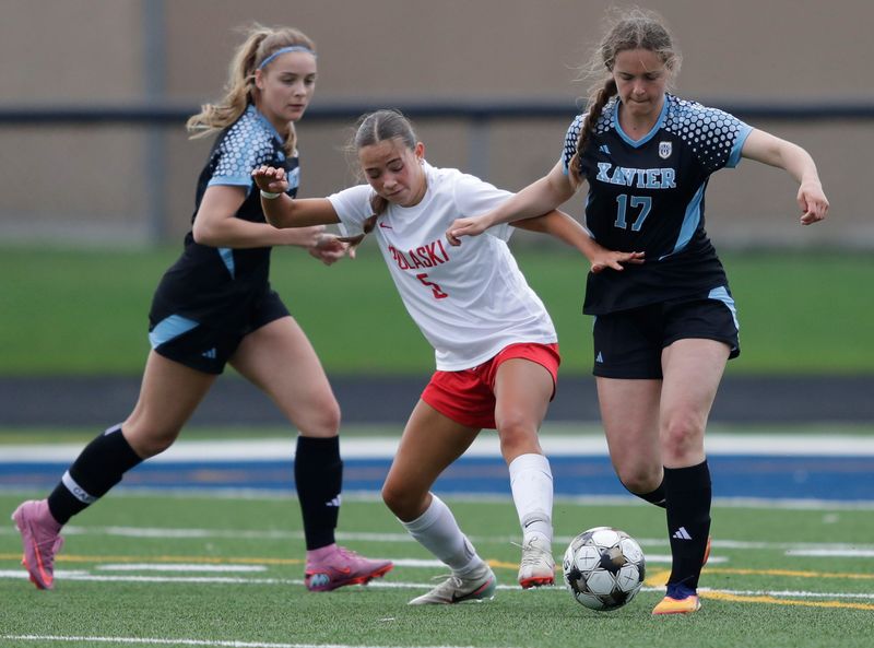 Pulaski High School's Anya Hasser (5) battles for control of the ball against Xavier High School's Eva Stankewicz (17) during their girls soccer game Friday, April 17, 2026, in Appleton, Wisconsin. Xavier won 3-1.