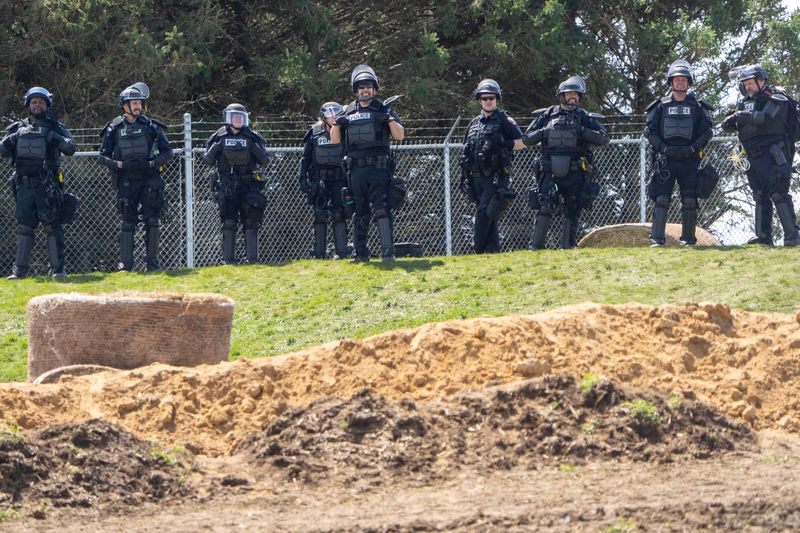 Law enforcement personnel stand between about 1,000 people and the medical research dog breeder Ridglan Farms Saturday, April 18, 2026 in rural Dane County near Blue Mounds, Wisconsin. Ridglan Farms is licensed by the state as a dog breeding operation. It breeds thousands of beagles and sells them to laboratories for medical and scientific testing and has operated for nearly 60 years.