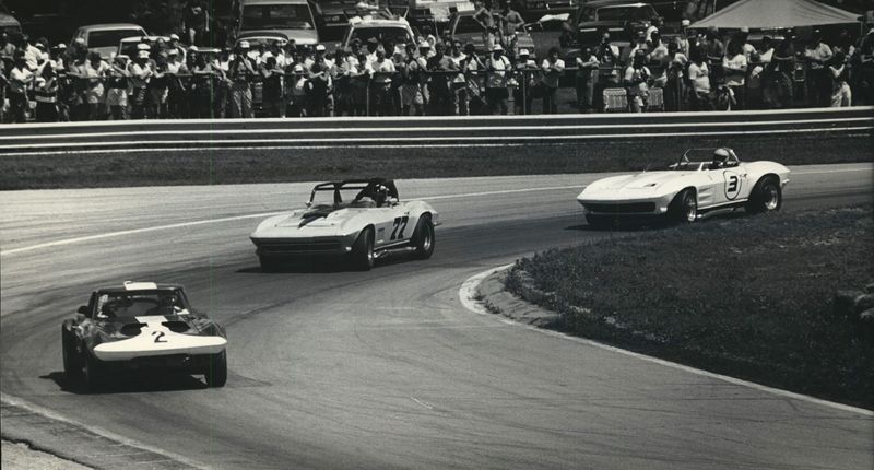 Fans watch from behind the guardrail as Robert Patterson leads Bill Morrison and Paul Canary during the 1986 vintage races at Road America.