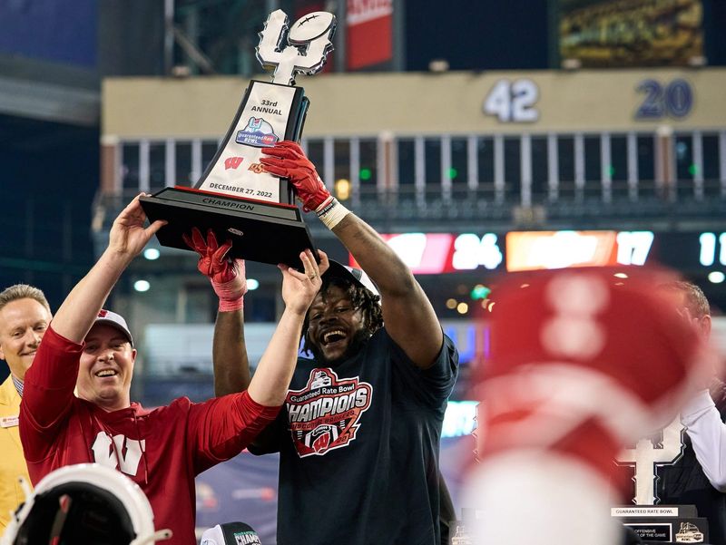 Defensive MVP Wisconsin Badgers linebacker Jordan Turner (54) and former interim head coach Jim Leonhard hold the champions trophy during the Guaranteed Rate Bowl Game at Chase Field on Tuesday, Dec. 27, 2022.

Ncaa Guaranteed Rate Bowl