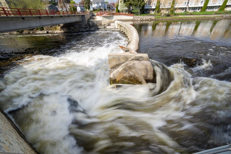 Water from the Milwaukee River rushes past a broken gate on the dam at Bridge Street Thursday, May 7, 2026, in Grafton, Wisconsin. Village officials said there is no threat to safety.