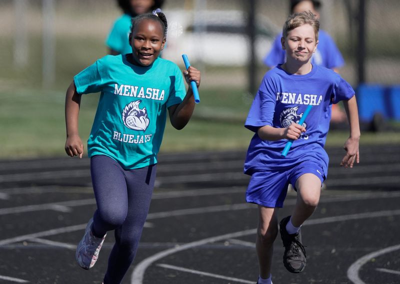 Menasha students run the second leg of a two-person relay at Calder Stadium.
