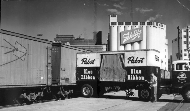 The downtown breweries operated elbow to elbow in the Milwaukee road's loading yards in 1956. Here Carl Osterland, a Pabst truck driver, awaits for his cargo to be loaded into a waiting refrigerator car. For years, Pabst and Schlitz have worked side by side in Milwaukee Road's loading yards.