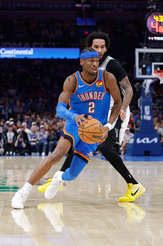 Jan 13, 2026; Oklahoma City, Oklahoma, USA; Oklahoma City Thunder guard Shai Gilgeous-Alexander (2) moves the ball around San Antonio Spurs forward Julian Champagnie (30) during the second half at Paycom Center. Mandatory Credit: Alonzo Adams-Imagn Images