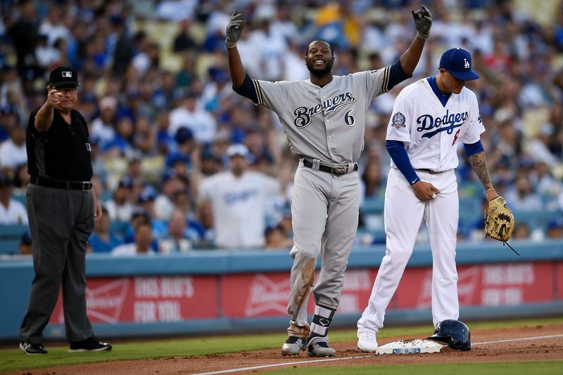 Milwaukee Brewers center fielder Lorenzo Cain (6) reacts after scoring off throwing error by Los Angeles Dodgers second baseman Brian Dozier after a triple during the first inning as third baseman Manny Machado (8) looks on at Dodger Stadium.