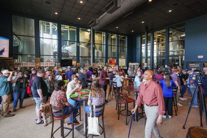 Patrons enjoy a variety of beer in the taproom at Wisconsin Brewing Company in Verona, Wisconsin, Saturday, May 23, 2026, as the final 80-barrel batch of Schlitz beer brews in the background.