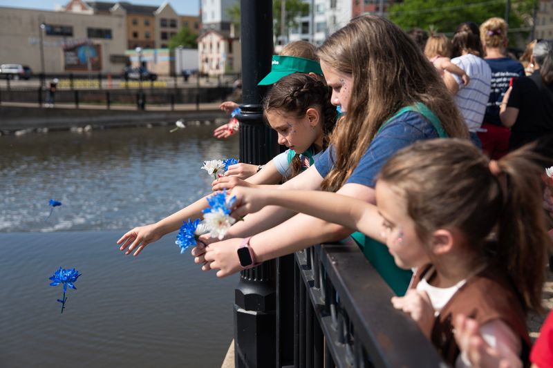 Girl Scouts Mia Buchholz, 10, Alexis Colburn, 11, and Penny Ludwig, 8, toss flowers into the Fox River to honor military veterans with their respective troops during the Memorial Day Riverside Ceremony on the morning of May 25, 2026 in Waukesha, Wisconsin.