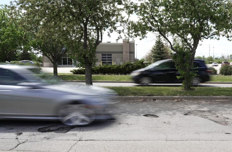 A motorists runs over a pothole at the entrance of the Walmart Superstore in Neenah before the potholes were filled with asphalt.