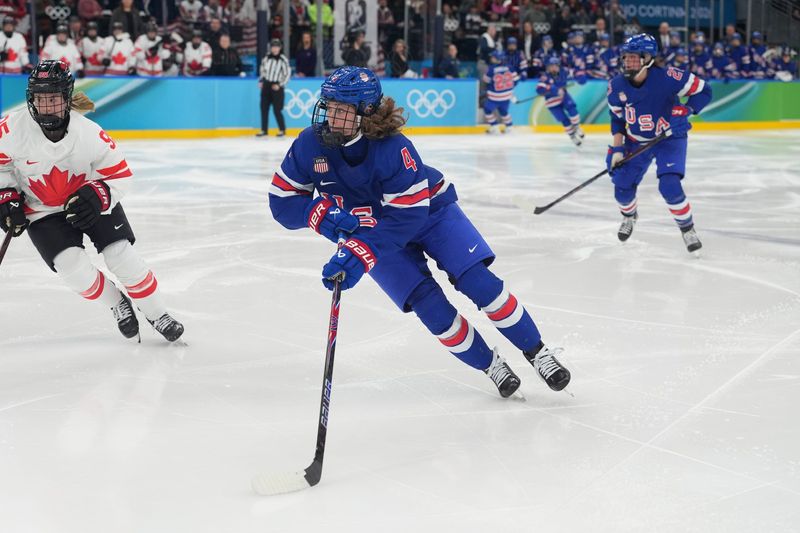 Feb 19, 2026; Milan, Italy; Caroline Harvey (4) of the United States controls the puck against Canada in overtime of the women's ice hockey gold medal game during the Milano Cortina 2026 Olympic Winter Games at Milano Santagiulia Ice Hockey Arena. Mandatory Credit: Amber Searls-Imagn Images