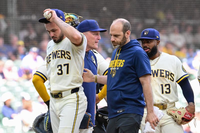 Brewers reliever DL Hall (37) leaves the game with an injury as he is escorted off the mound against the Giants by athletic trainer Brad Epstein in the fifth inning on Thursday, June 4 at American Family Field.