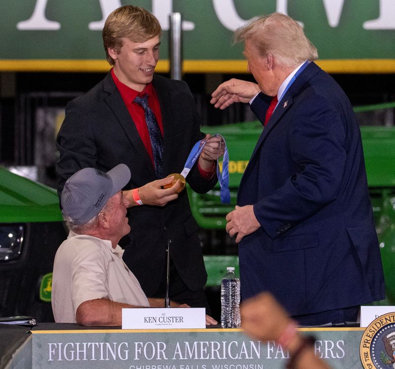 Olympic gold medalist Jordan Stolz puts on his gold medals on President Trump Friday, June 5, 2026 at Custer Farms Inc. in Chippewa Falls, Wisconsin. Trump promoted his administration's efforts to lower costs and open new trade markets for farmers and to boost the economy in rural areas through tax incentives for investors in such areas of the country. It was the president’s first trip to the Wisconsin since being reelected in 2024.