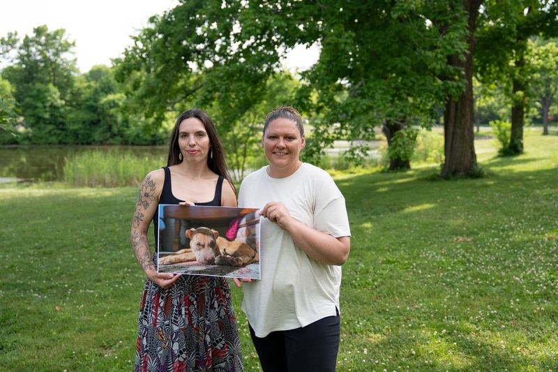 Danielle Dietz, left, and Alicia Hegedus pose for a portrait on June 9 while holding a photo of Ranger, a dog shot and injured by a Thiensville police officer.