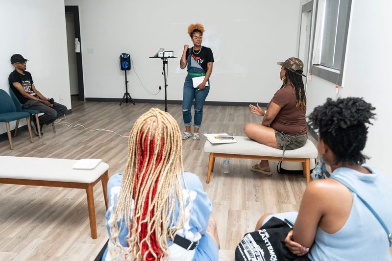 Koren Dennison leads a discussion about an Intelexual Media video about the evolution of Black women’s hair during a My Kousin’s House “Wash Day for Black Women” event at Third Space Collective MKE on June 13, 2026, in Milwaukee, Wisconsin. Dennison started My Kousin’s House events to build community and a third space.