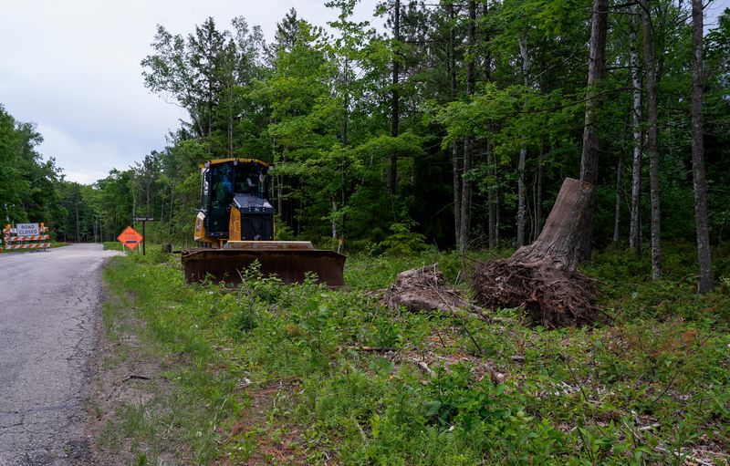 Heavy construction equipment and an uprooted tree stump are seen June 16, along South Norway Road in Potawatomi State Park near Sturgeon Bay. The Wisconsin Department of Natural Resources is being sued over claims that the road construction project on South Norway Road and Shoreline Road in the park is not part of its master plan as required by the state.