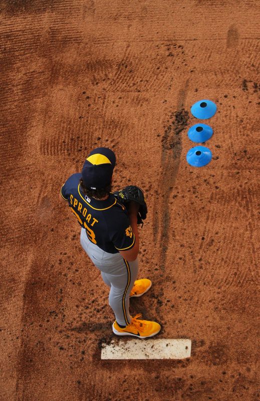 Milwaukee Brewers pitcher Brandon Sproat warms up with a row of blue cones to help him keep his direction toward home plate.