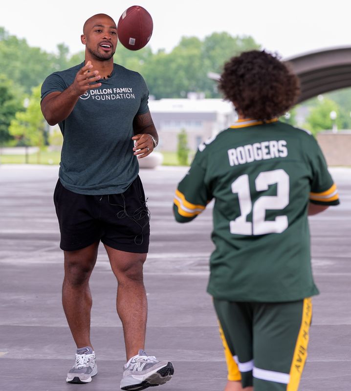 Former Green Bay Packers and current Carolina Panthers running back AJ Dillon tosses a football to 12-year-old Jordan Rodriguez June 24 at Howard Commons Activity Complex in Howard. Dillon was there to present a check for $10,925 to Families of Children with Cancer.