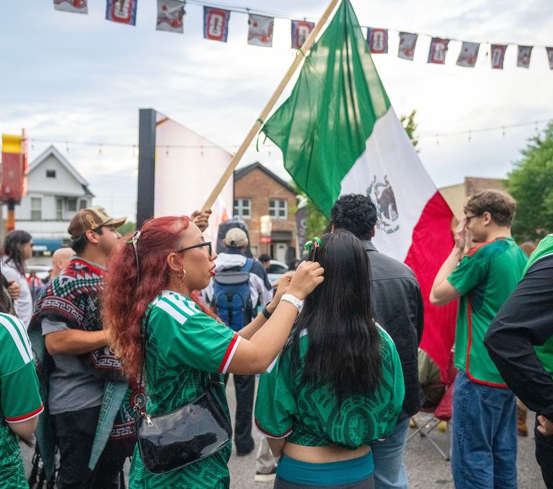 Girl fixes her friend's hair ribbon in Mexico's flag colors during a World Cup watch party at Zocalo Food Truck Park on the south side in Milwaukee, Wisconsin on June 25, 2026. - Alyssa N. Salcedo / Milwaukee Journal Sentinel