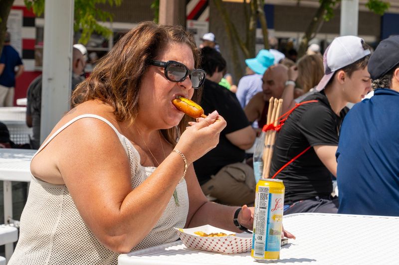 Melissa Pieters eats a corn dog on Summerfest grounds in Milwaukee, Wisconsin on June 25, 2026.