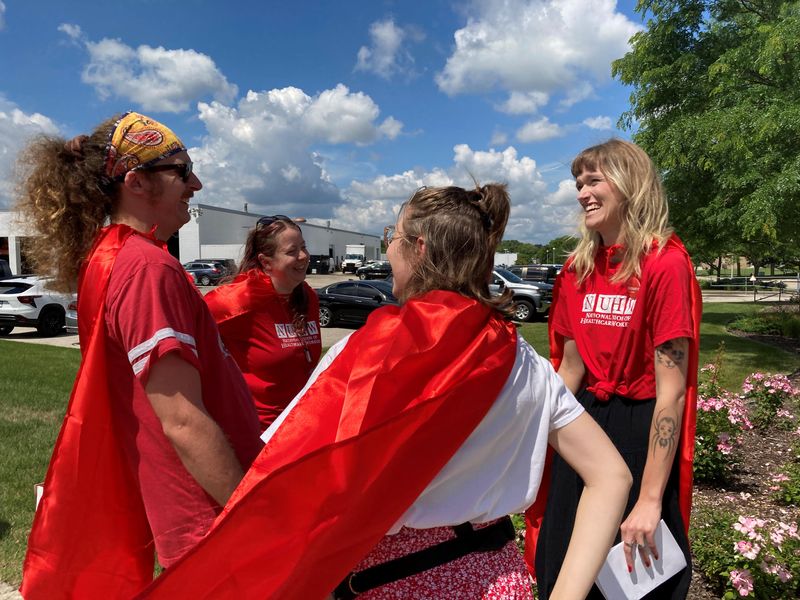 Delaney O'Connor, far right, wears a cape Thursday, June 25, 2026 outside a Rogers Behavioral Health outpatient clinic in West Allis, in protest of recent firings -- including her own -- that a labor union alleges were retaliatory. One of the firings related to a worker wearing a cape on the day of the union election.