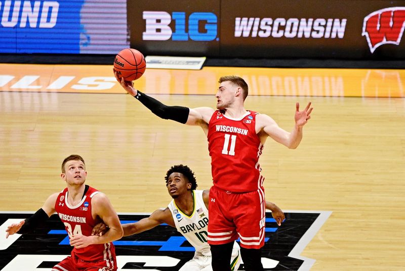 Mar 21, 2021; Indianapolis, Indiana, USA; Wisconsin Badgers forward Micah Potter (11) grabs a loose ball above guard Brad Davison (34) and Baylor Bears guard Adam Flagler (10) during the second half in the second round of the 2021 NCAA Tournament at Hinkle Fieldhouse. The Baylor Bears won 76-63. Mandatory Credit: Marc Lebryk-USA TODAY Sports