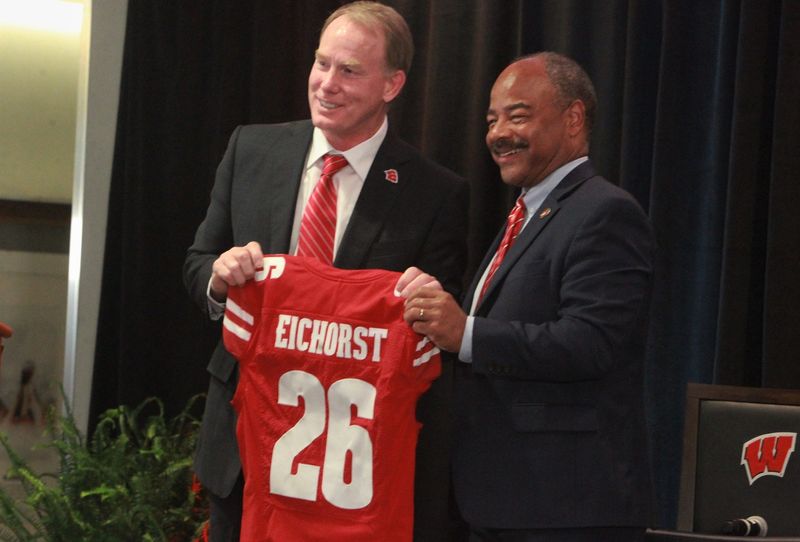 University of Wisconsin athletic director Shawn Eichorst (left) and interim chancellor Eric Wilcots pose with a Badgers football jersey during a meet-and-greet event for Eichorst at the Champions Club inside Camp Randall Stadium in Madison, Wisconsin on Tuesday July 7, 2026.