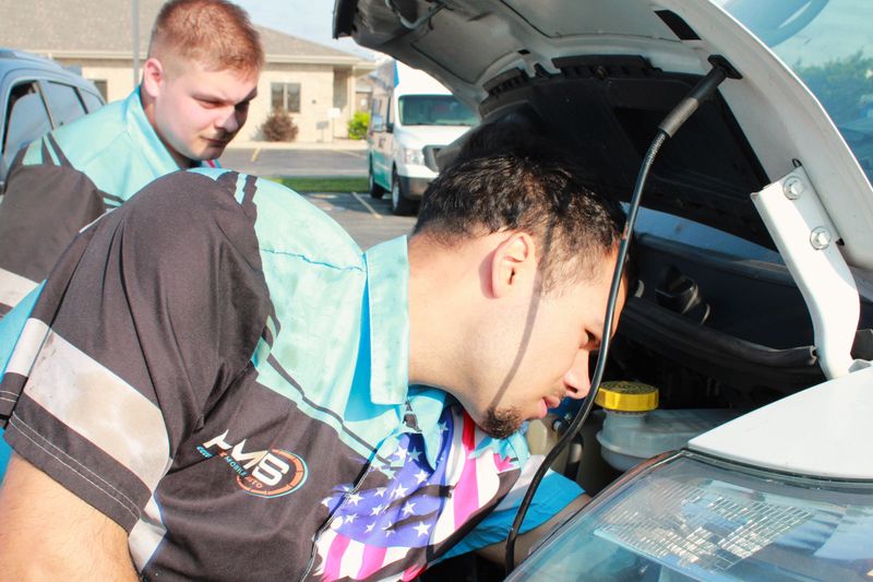 Gavin Geller (back) and Mason Rivera (front), mechanics for HMS Mobile Auto, work on a vehicle on July 21.