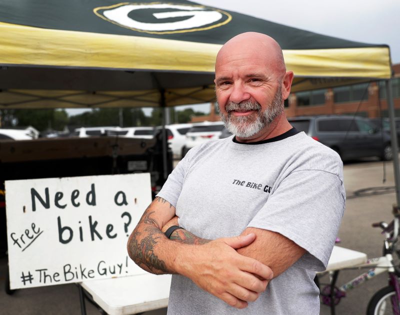 Greenleaf resident Adam O'Connell, known as The Bike Guy, offers kids loaner bicycles to try their luck getting a Green Bay Packers player to ride it during the DreamDrive at training camp July 31 at Lambeau Field.