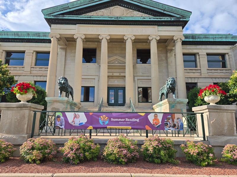 The Oshkosh Public Library, as seen from the south side of the building, displays a promotional summer reading banner in June 2026.