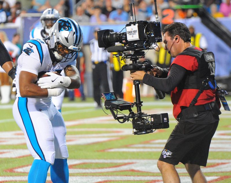 Carolina's AJ Dillon rocks the ball in a cradle for the TV camera after scoring a touchdown in the 2026 HOF Game against the Arizona Cardinals Thursday August 6, 2026 at Tom Benson Stadium.  Michael Skolosh/Special to the Canton Repository