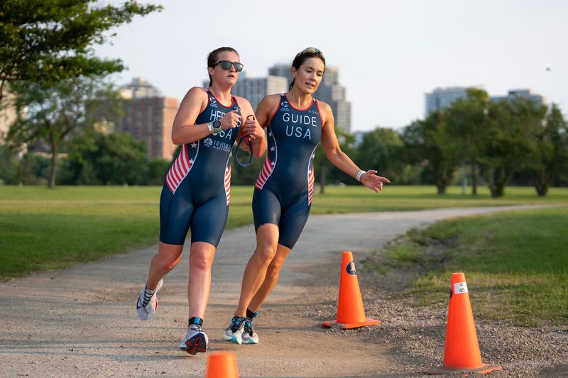 McClain Hermes and her guide, Jenna Haufler, run through Veterans Park toward the finish line of the USA Triathlon Nationals on Aug. 9, 2026 in Milwaukee, Wisconsin.