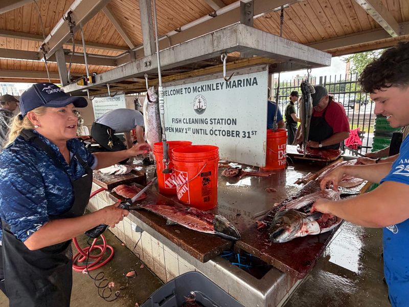 Volunteers Brenda Rosin-Schaff and Will Awve clean fish Aug. 9, 2026 at the Brew City Salmon Tournament in Milwaukee. Anglers in the event donated 2,080 pounds of salmon and trout to the Hunger Task Force.
