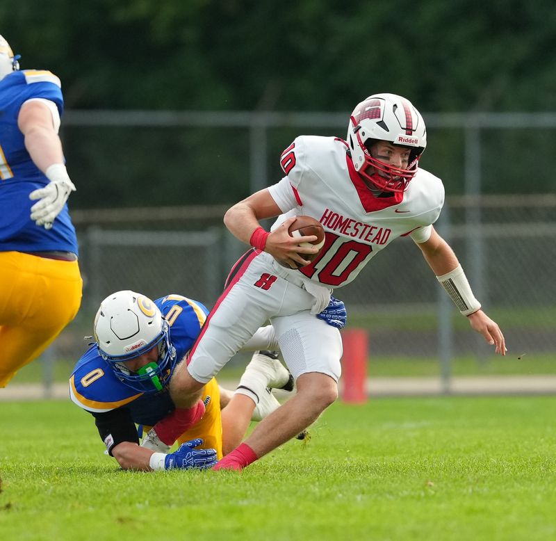 Homestead quarterback Lee Zortman (10) escapes Germantown's Connor Meyers (0) during the game against Germantown on August 21, 2026, in Germantown, Wisconsin.